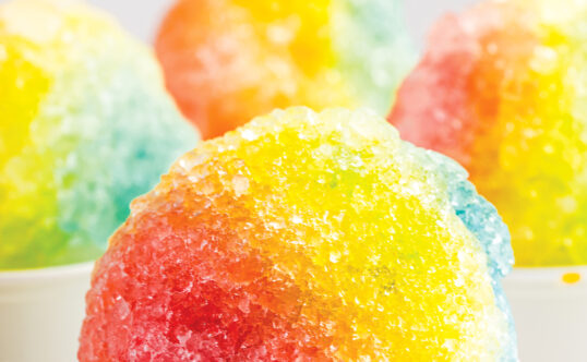 Multiple servings of shaved ice. The maker has been careful to apply flavors in a way that creates an ombre.
